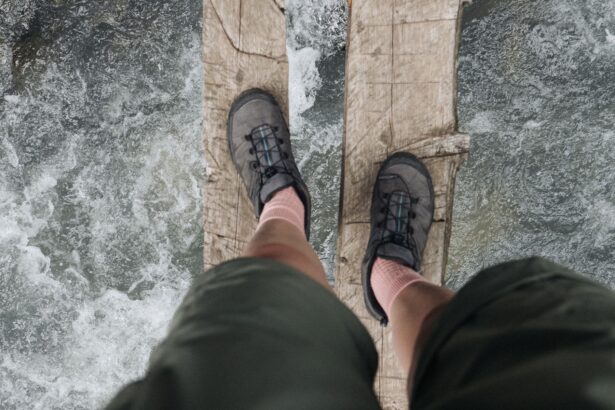 Hiker in grey trail shoes balancing on a wooden log above a flowing river