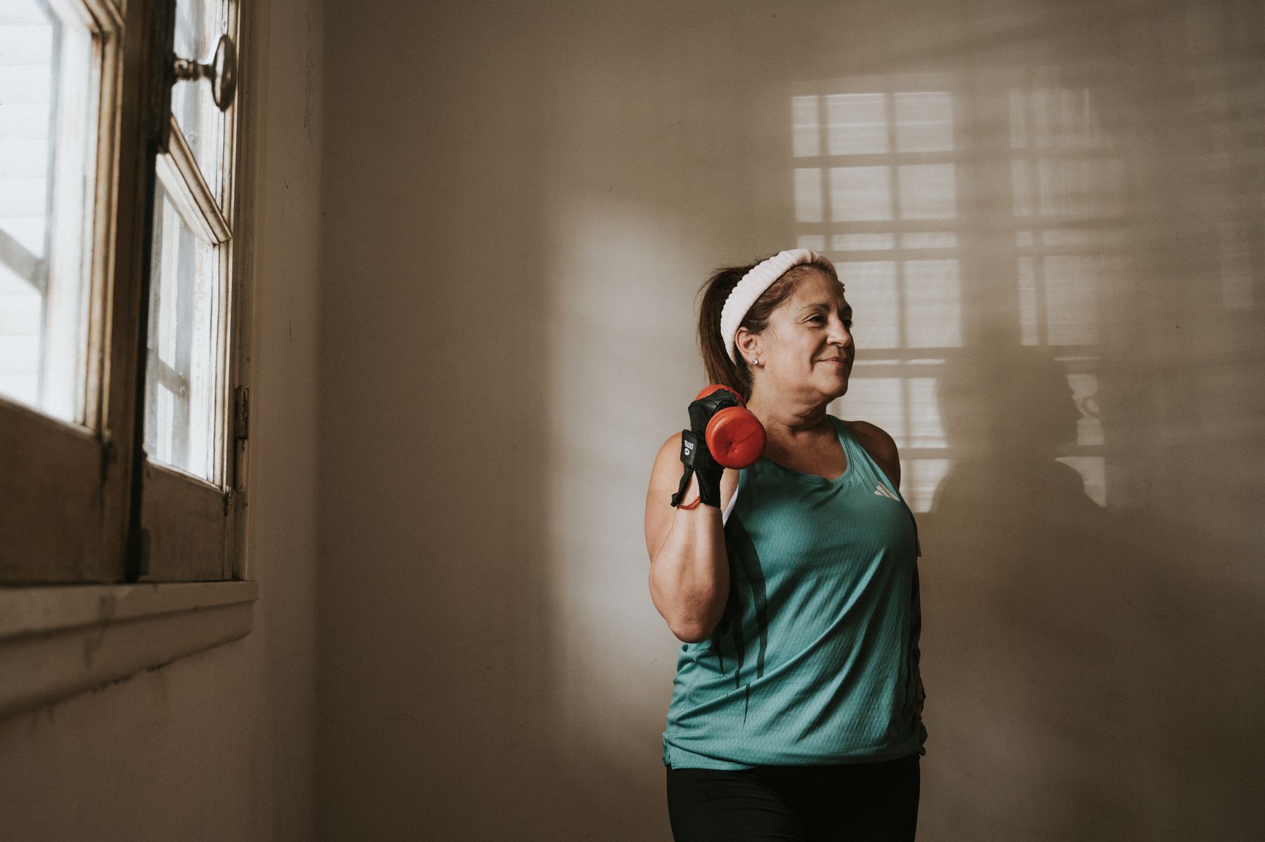 Middle-aged woman in workout clothes lifting a dumbbell indoors