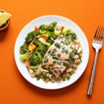 Salmon fillet with herbs on quinoa beside roasted broccoli
